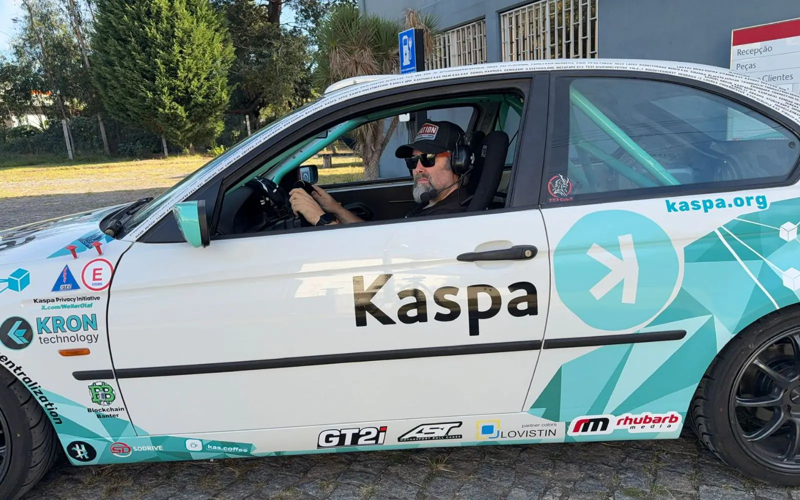 The driver belted into the bucket seat of the finished rally car, headset on and hands on the wheel