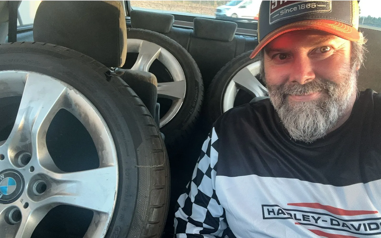 The driver sat beside four BMW alloy wheels loaded into a car