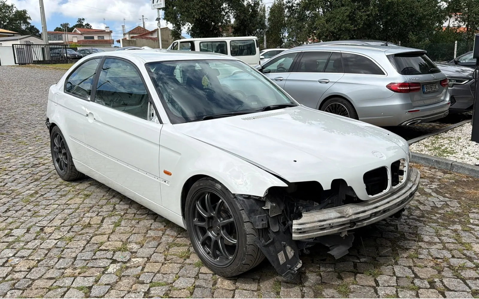 The car back outside on the cobbles in its new white paint, front bumper still removed and black rally wheels fitted